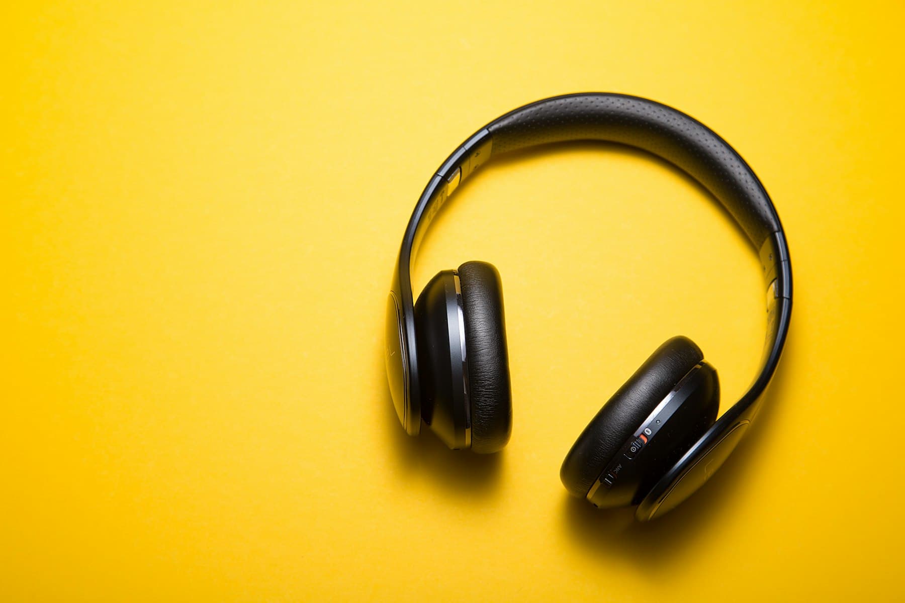 Vanta V1 Wireless headphones in matte black, photographed on a signal-yellow background